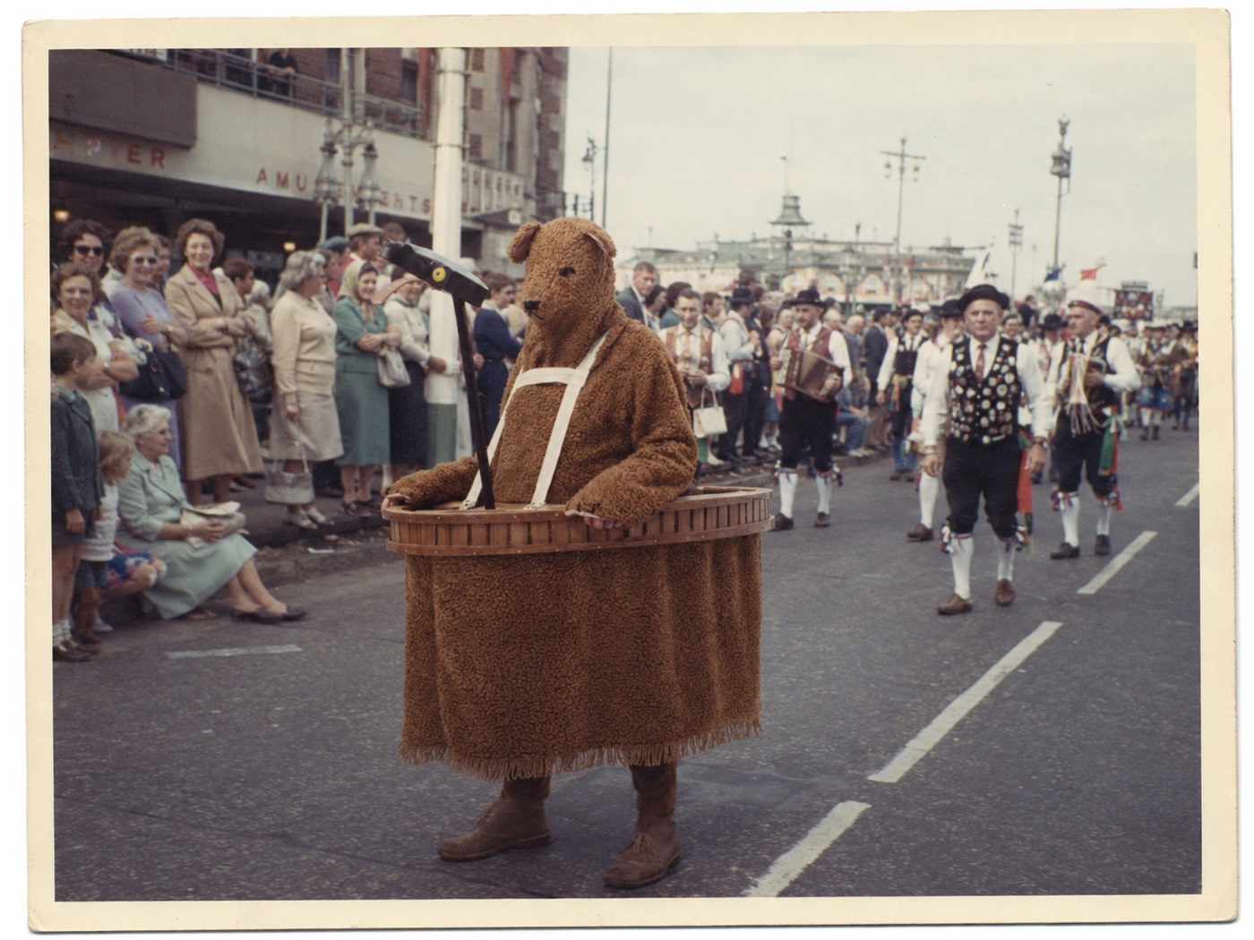The Bear walking ahead of musicians in a seafront procession