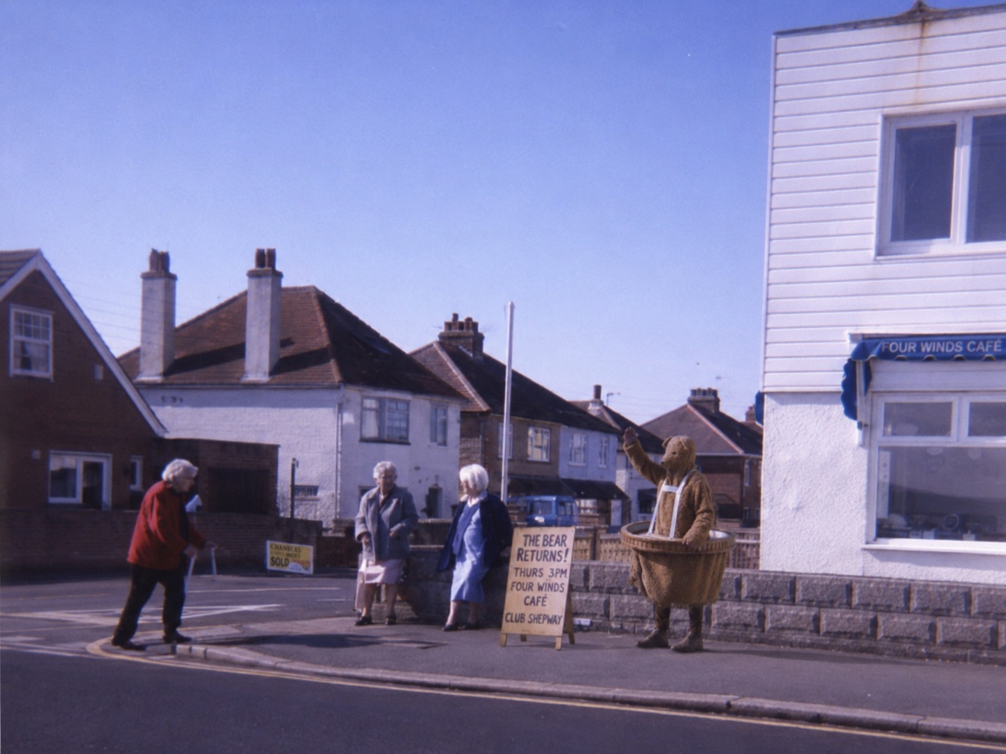 The Bear outside the Four Winds Cafe beside a hand-painted return notice