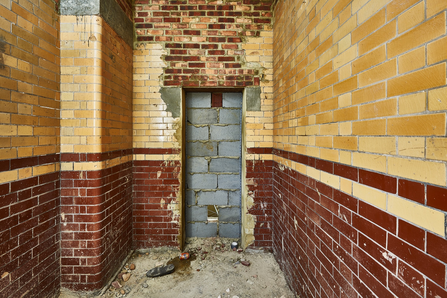 Yellow and red tiled interior of the former Folkestone lock-up with a bricked-up doorway