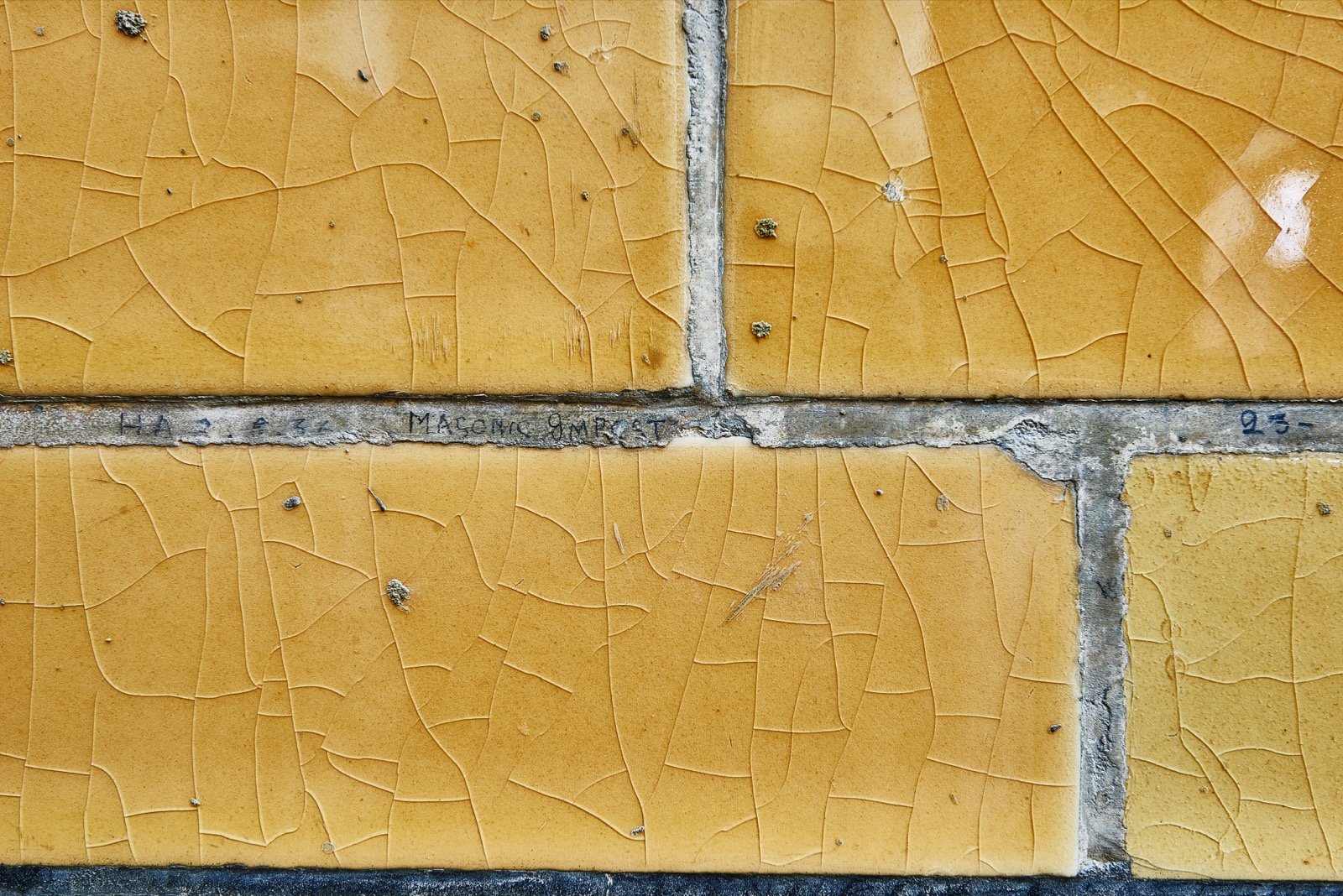 Close detail of glazed yellow tiles bearing faint pencil writing