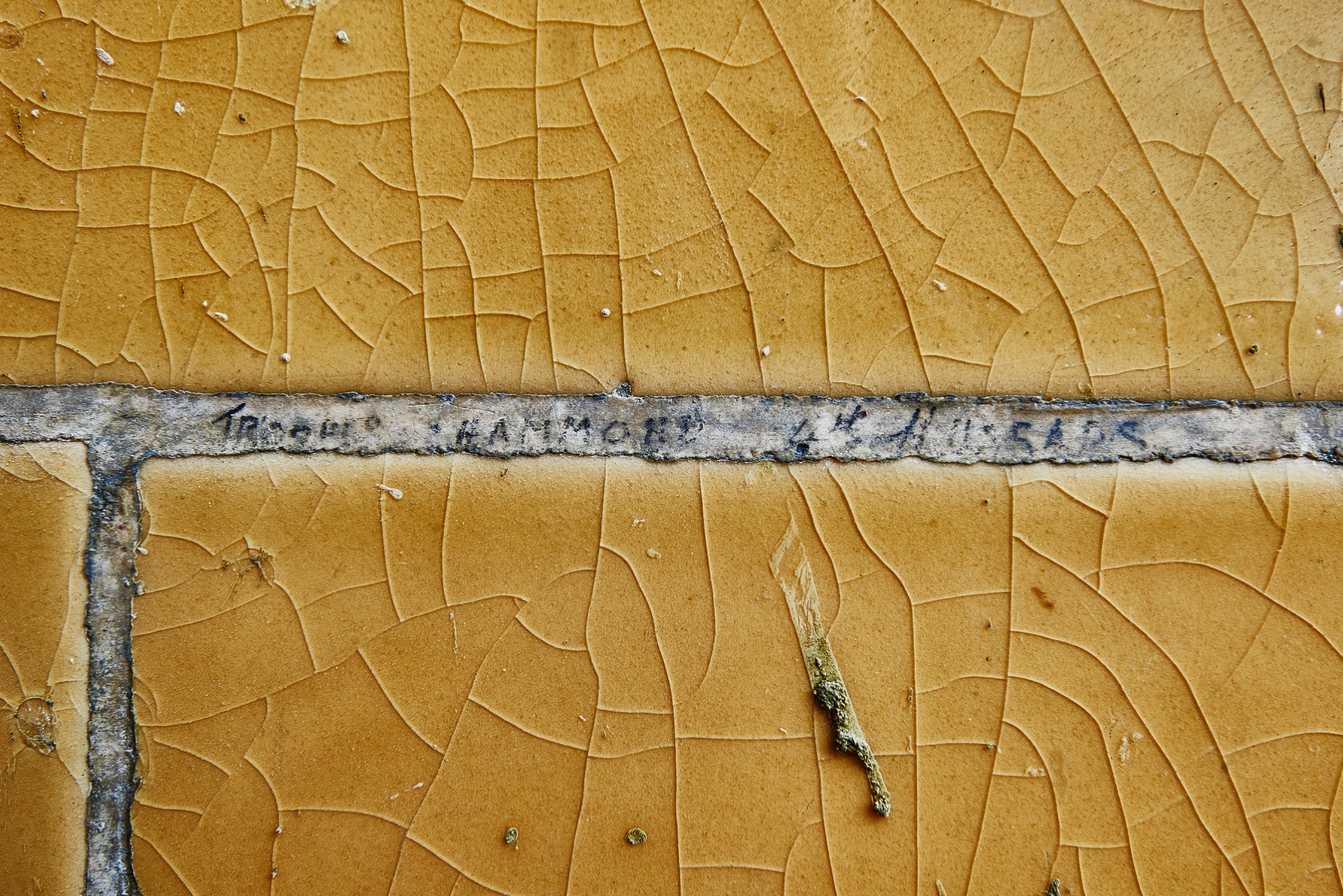 Close detail of yellow wall tiles bearing faint pencil marks