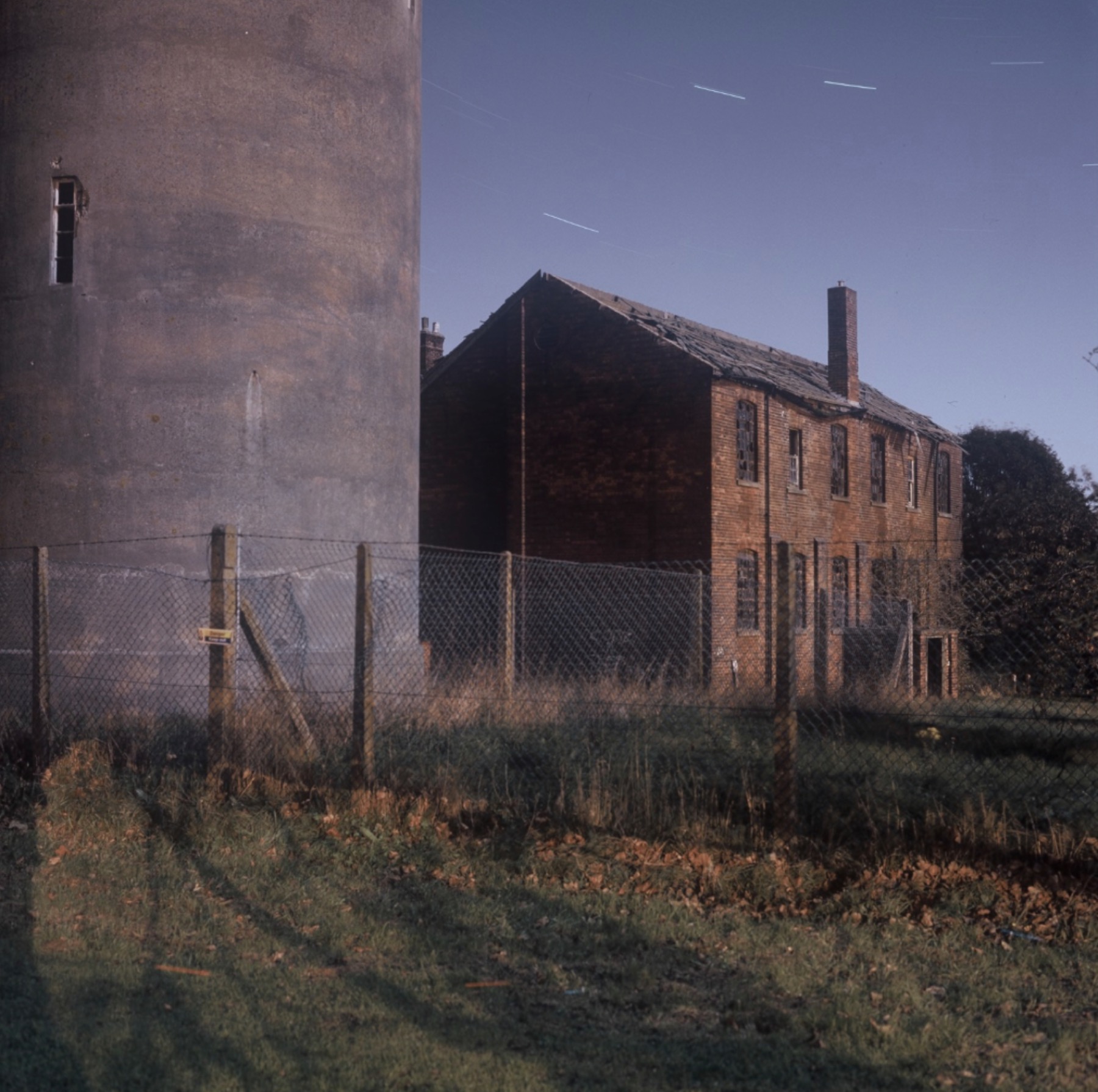 Former barracks building behind a chain-link fence