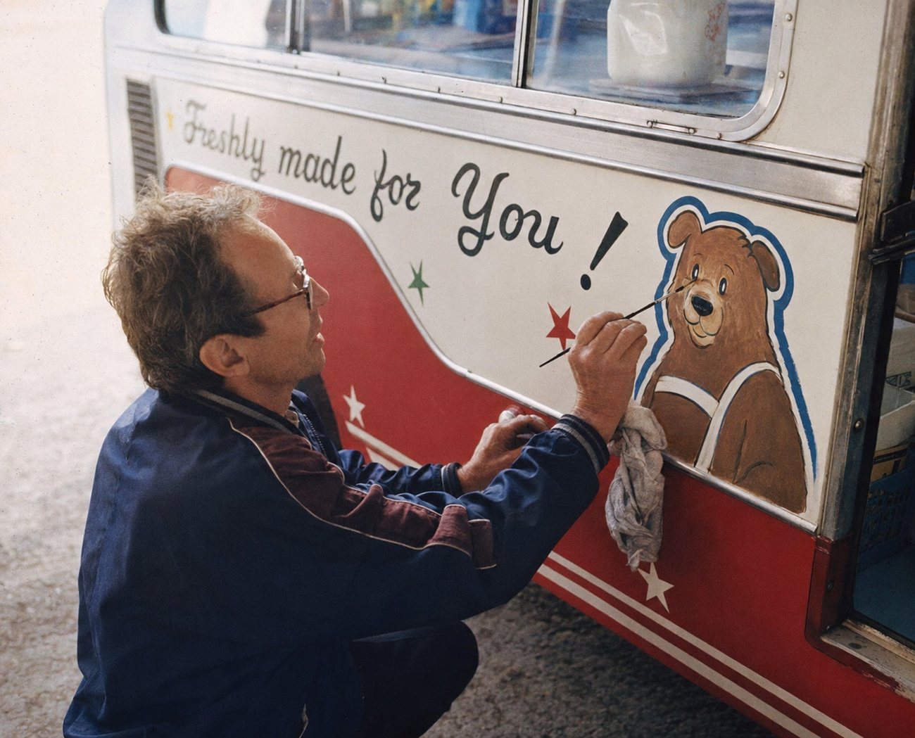 Signwriter painting the Bear on a Rio's ice cream van